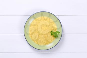 plate of raw couscous on white wooden background