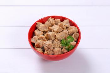 bowl of soy meat cubes on white wooden background