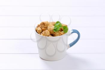 mug of soy meat cubes on white wooden background