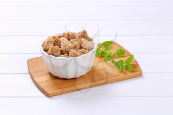 bowl of soy meat cubes on wooden cutting board