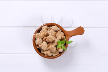 saucepan of soy meat cubes on white wooden background