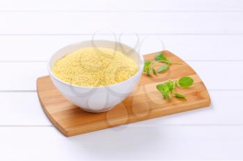bowl of raw couscous on wooden cutting board