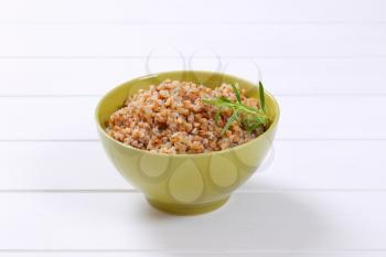 bowl of cooked buckwheat on white wooden background