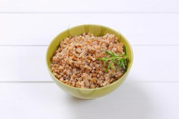 bowl of cooked buckwheat on white wooden background