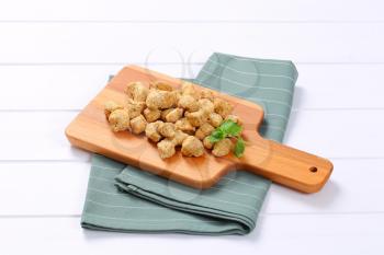 pile of soy meat cubes on wooden cutting board