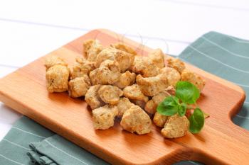 pile of soy meat cubes on wooden cutting board - close up