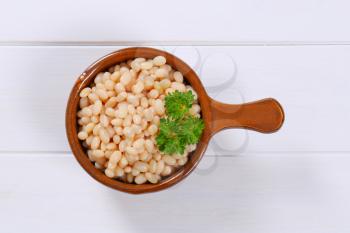 saucepan of canned white beans on white wooden background