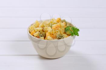 bowl of cooked colored pasta on white wooden background