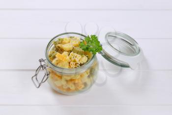 jar of cooked colored pasta on white wooden background