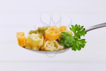 spoon of cooked colored pasta on white wooden background