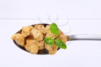 spoon of soy meat cubes on white wooden background