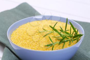 bowl of raw millet on grey place mat - close up