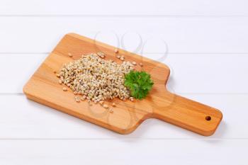 pile of cooked pearl barley on wooden cutting board