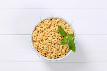 bowl of honey cereal rings on white wooden background