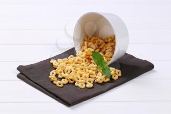 bowl of honey cereal rings spilt out on grey place mat