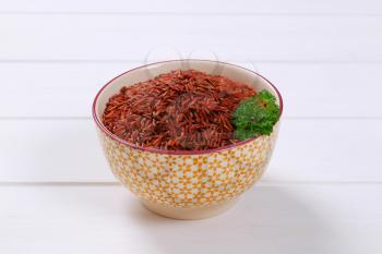 bowl of red rice on white wooden background