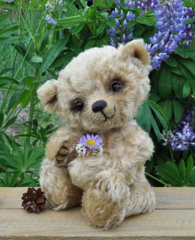 Handmade, the sewed toy: teddy bear Lucky on a little board among flowers