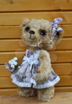 Handmade, the sewed toy: teddy-bear Lucky before a wooden wall