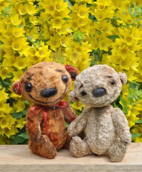 Teddy bears on a board among flowers. Handmade, the sewed plush toys