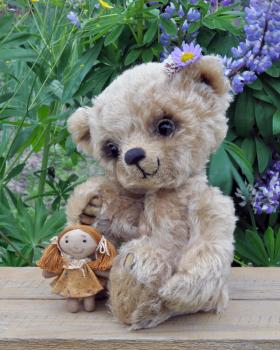 Teddy-bear Lucky with a rag doll on the board against a background of flowers. Handmade, the sewed toy