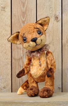 Ron fox cub on the background of a wooden plank wall. Handmade, the sewed plush toy