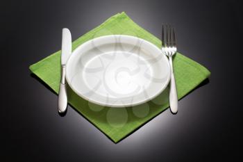 plate and fork with knife at napkin cloth on black background