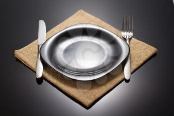plate and fork with knife at napkin cloth on black background