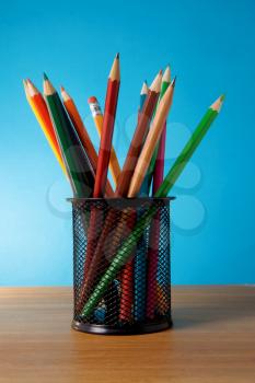 holder basket full of colored pencils standing on green background
