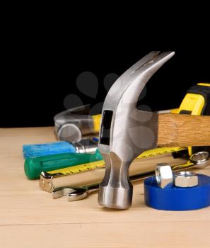 hammer and other construction tools on wooden brick isolated on black