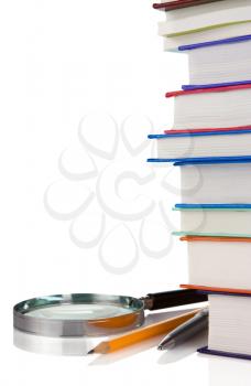 pile of new books, pen and magnifying glass isolated on white background