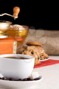 coffee beans, cup and grinder on sacking with cookies