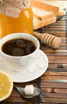 coffee, honey, lemon and bread on straw table