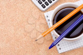 pen, pencil and cup of coffee on checked notebook