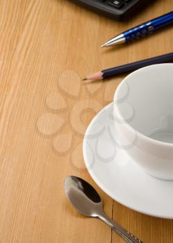 pen, calculator and cup of coffee on wooden table