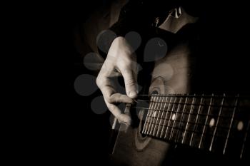 man playing guitar at black background
