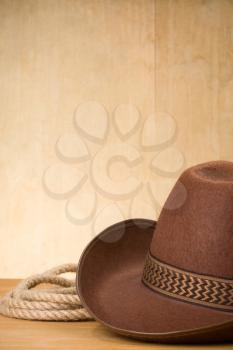 brown cowboy hat and rope on wood background