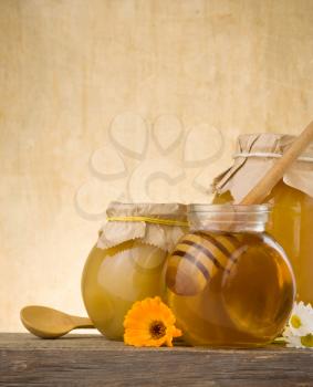 jar of honey and stick on wood background