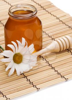 pot of honey and flower on straw background