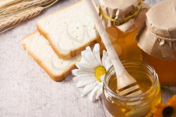 honey, flowers, spike and bread on table