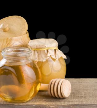 jar full of honey and stick isolated on black background