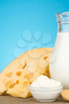 swiss cheese and milk products on wood at blue background