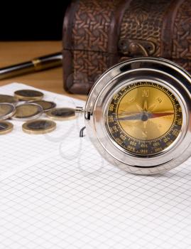 compass, pen and coin on checked notebook