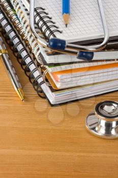 medical stethoscope with notebook at wood table background