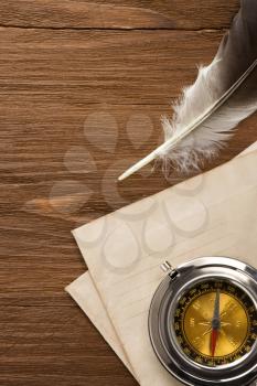 compass and ink feather at envelope on vintage wood background texture