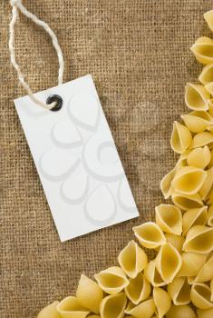 raw pasta and price tag on sack hessian burlap as background