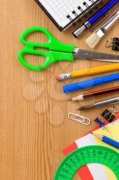 school supplies and checked notebook on wood background