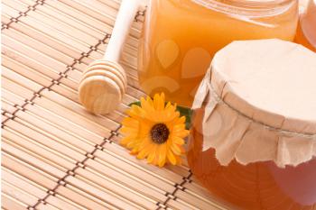 pots of honey and flower on straw background