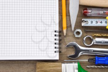 set of tools and notebook on wood texture background