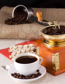 coffee beans, honey, cup and grinder on sacking