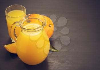 glass pitcher and orange juice on wooden background